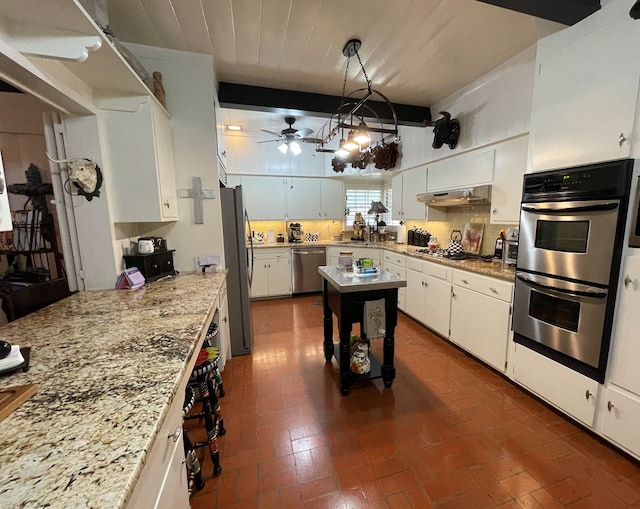 kitchen featuring white cabinetry, brick floor, under cabinet range hood, a ceiling fan, and stainless steel appliances