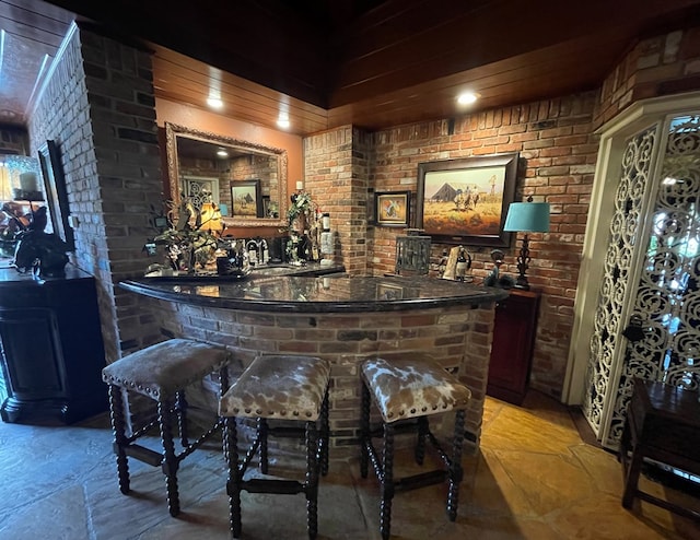 bar with indoor wet bar, brick wall, and a sink