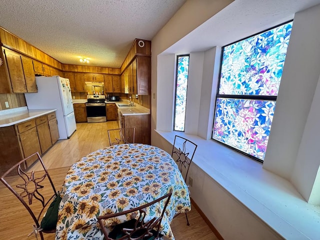 kitchen featuring a textured ceiling, light countertops, stainless steel electric range, and brown cabinets