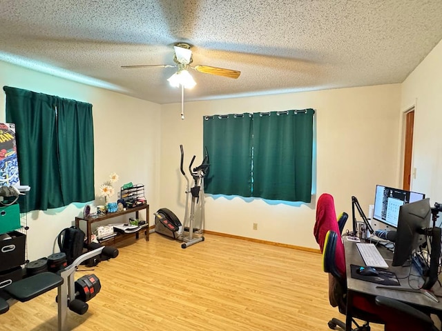 interior space featuring a textured ceiling, wood finished floors, a ceiling fan, and baseboards