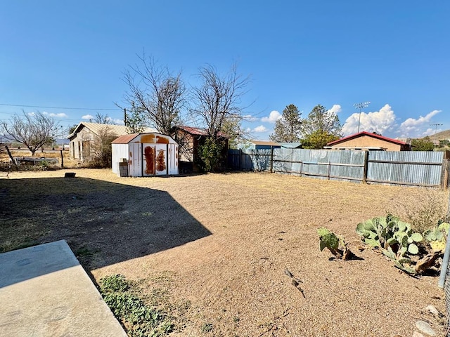 view of yard featuring a shed, a fenced backyard, and an outbuilding