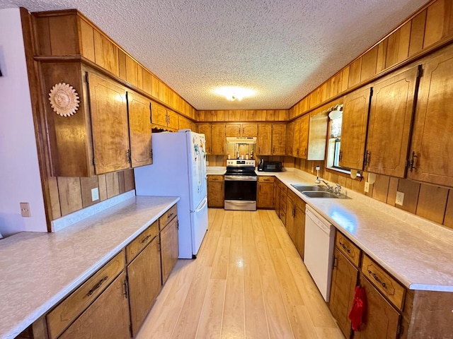 kitchen featuring white appliances, brown cabinets, and a sink