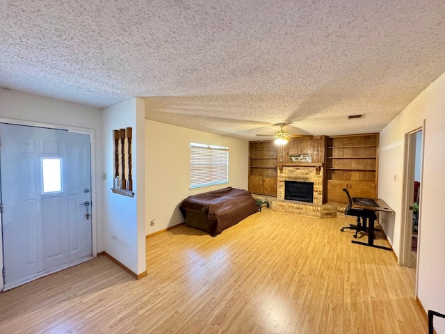 entryway with light wood-type flooring, a fireplace, a textured ceiling, and baseboards