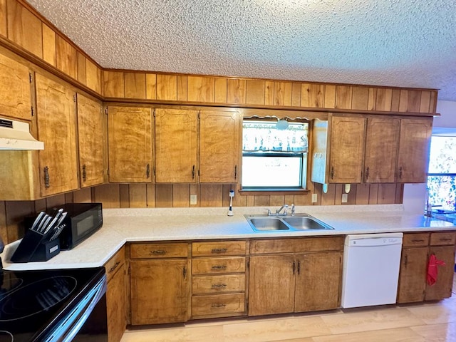 kitchen featuring range with electric cooktop, dishwasher, under cabinet range hood, black microwave, and a sink