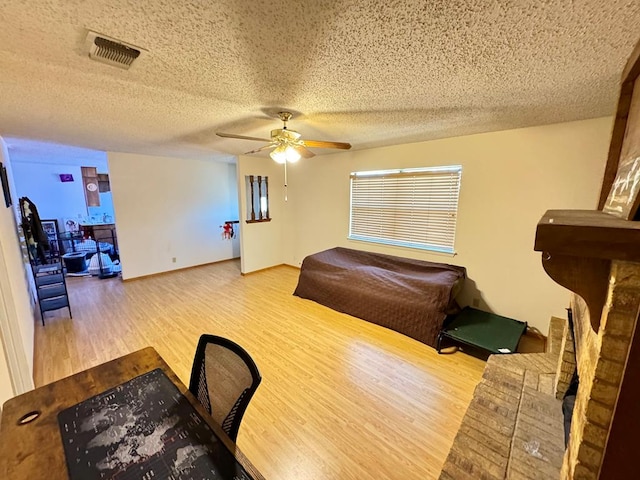 bedroom with baseboards, visible vents, a ceiling fan, wood finished floors, and a textured ceiling