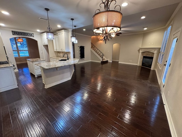 1205 Silverton Dr, Midland, TX 79705 - kitchen featuring arched walkways, a glass covered fireplace, white cabinets, open floor plan, and dark wood-style flooring