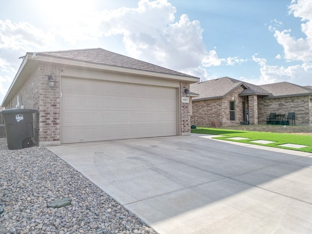 view of front of property with concrete driveway, brick siding, a shingled roof, and a garage