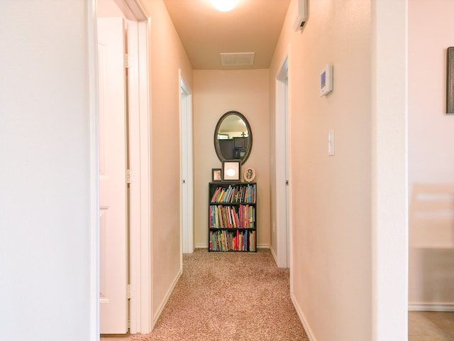 corridor with baseboards, light colored carpet, and visible vents