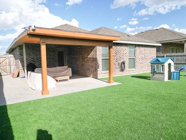 rear view of property with brick siding, a patio area, fence, and a yard