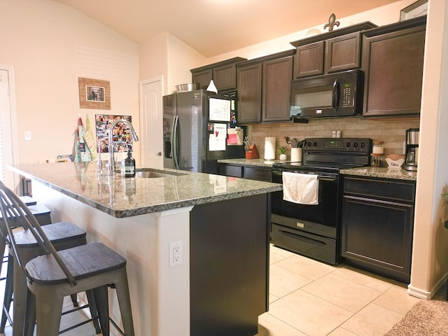 kitchen featuring stone countertops, a kitchen bar, tasteful backsplash, a sink, and black appliances
