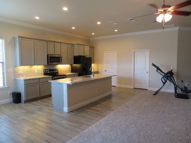 1812 Masquerade Blvd, Odessa, TX 79765 - kitchen featuring appliances with stainless steel finishes, gray cabinetry, crown molding, an island with sink, and backsplash