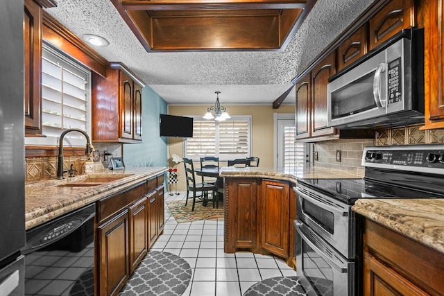 1324 Pagewood Ave, Odessa, TX 79761 - kitchen with appliances with stainless steel finishes, a chandelier, decorative backsplash, light tile patterned flooring, and light stone countertops
