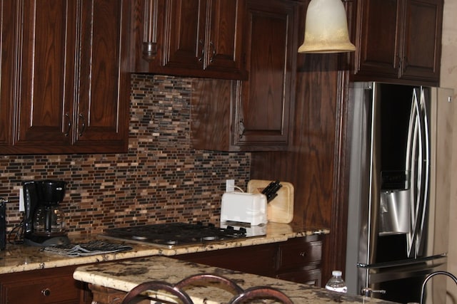 kitchen with appliances with stainless steel finishes, backsplash, dark brown cabinetry, and light stone countertops