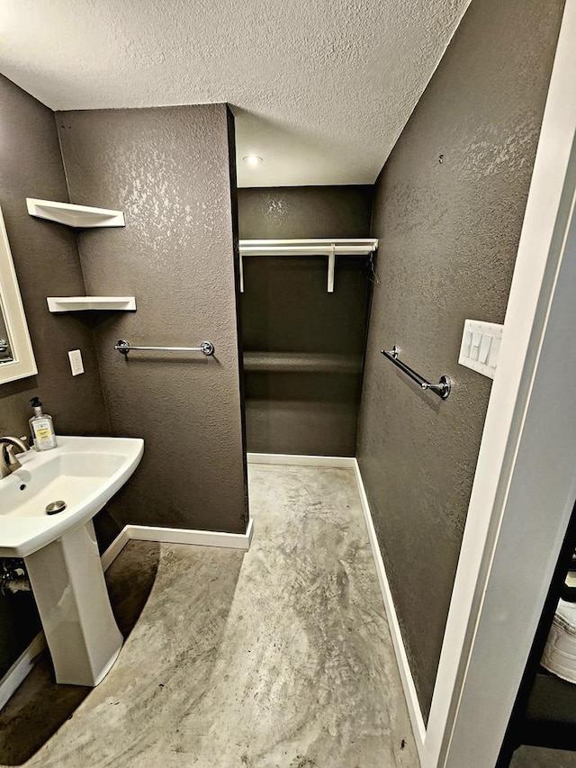 408 W 2nd St, Marfa, TX 79843 - bathroom featuring baseboards, a textured ceiling, a spacious closet, and a textured wall