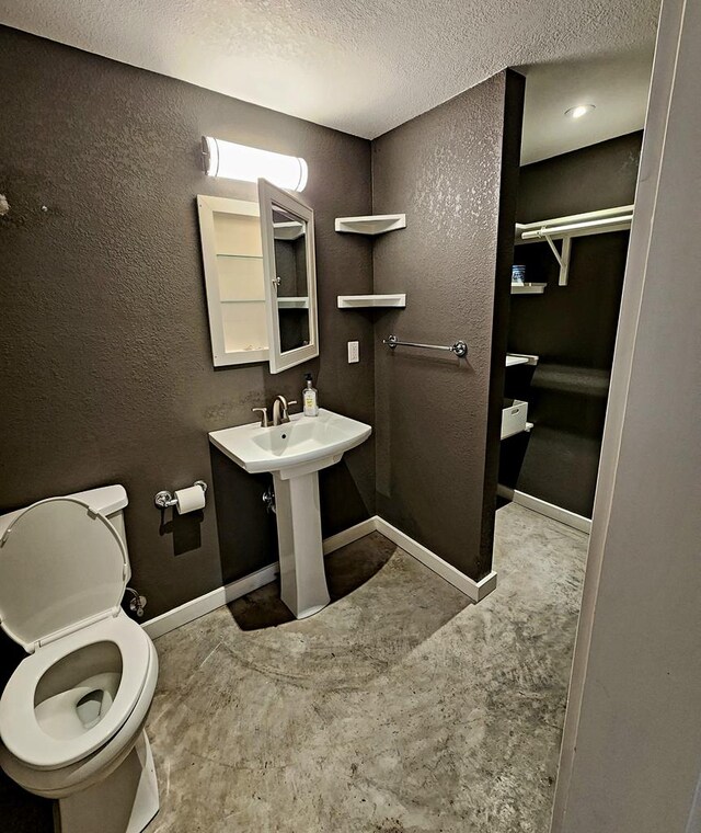 408 W 2nd St, Marfa, TX 79843 - half bathroom with concrete floors, toilet, a textured ceiling, baseboards, and a textured wall