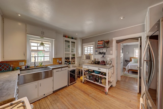 408 W 2nd St, Marfa, TX 79843 - kitchen with stainless steel refrigerator, wine cooler, light wood-style floors, white cabinetry, and ornamental molding