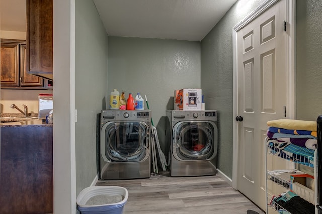 laundry room featuring sink, light hardwood / wood-style floors, and independent washer and dryer