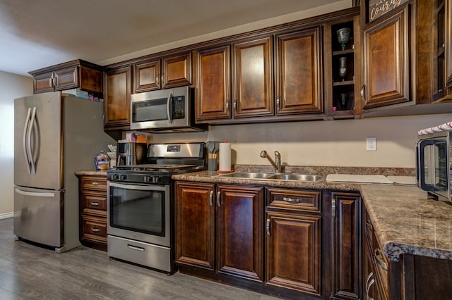 kitchen with dark brown cabinets, appliances with stainless steel finishes, dark hardwood / wood-style flooring, and sink