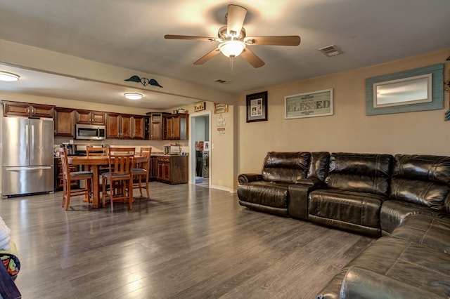 living room featuring ceiling fan and dark wood-type flooring