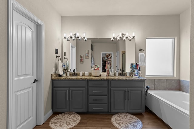 7028 Xit Ranch Rd, Odessa, TX 79765 - bathroom featuring double vanity, a bath, wood finished floors, and a closet