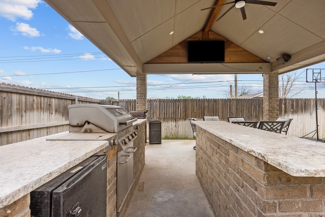 view of patio with a fenced backyard, an outdoor kitchen, and a ceiling fan