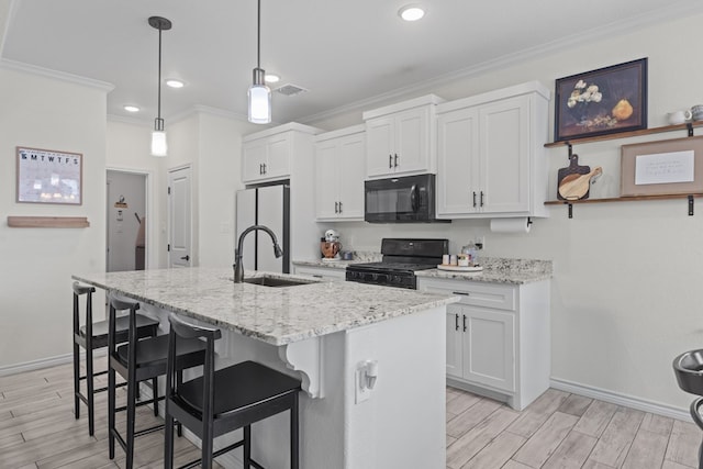 kitchen with a sink, crown molding, light wood-style flooring, and black appliances