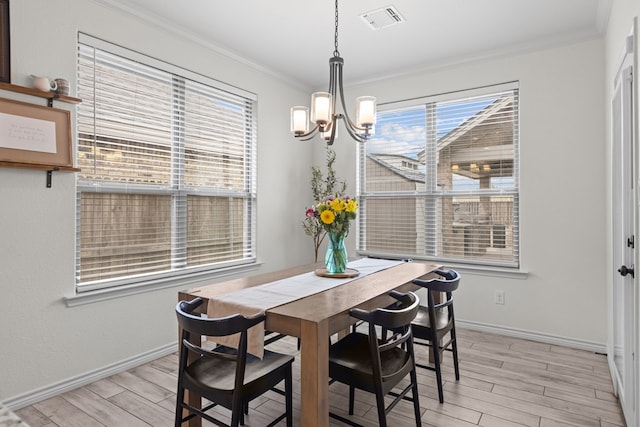 dining area featuring a chandelier, light wood-style flooring, crown molding, and visible vents