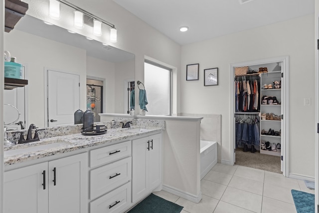 full bathroom featuring tile patterned flooring, double vanity, a sink, and a walk in closet