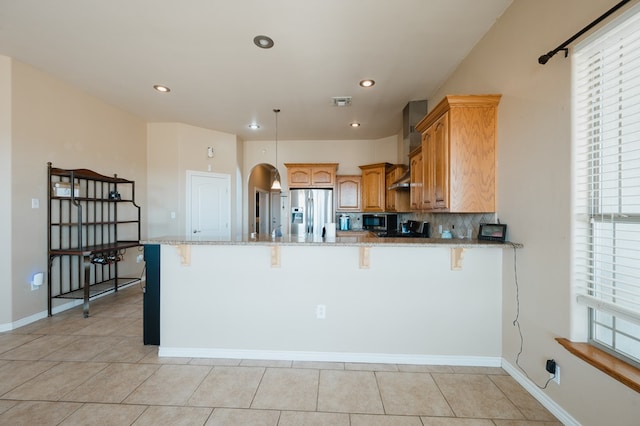 kitchen featuring stainless steel refrigerator with ice dispenser, light stone counters, kitchen peninsula, and a breakfast bar area