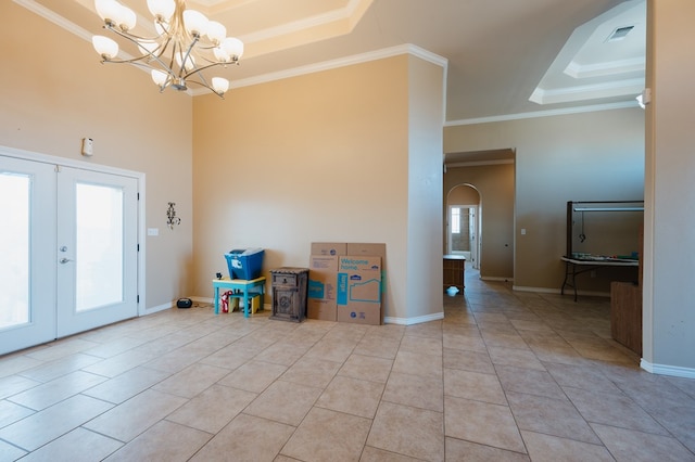 interior space featuring a chandelier, crown molding, a raised ceiling, and french doors