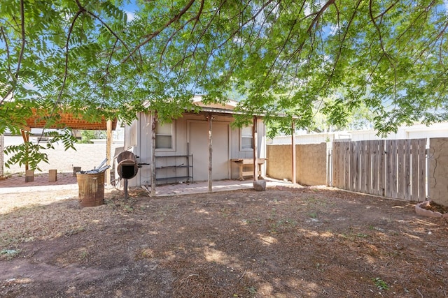 rear view of house with fence and an outbuilding