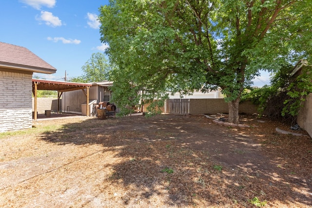 view of yard featuring fence, driveway, and a carport