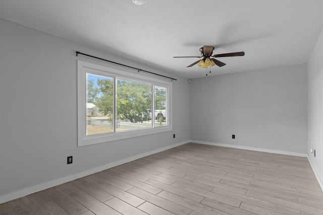 spare room with ceiling fan, baseboards, and light wood finished floors