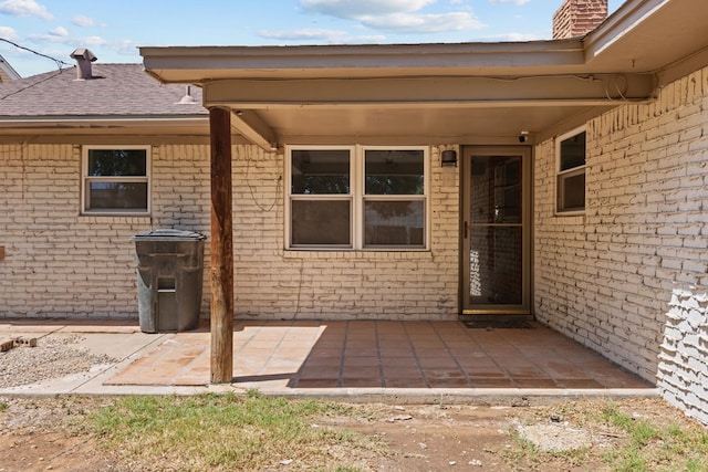 property entrance featuring a patio, brick siding, and a chimney