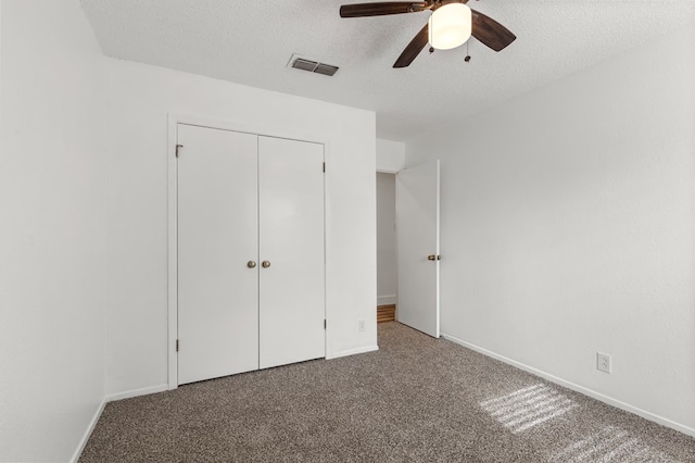 unfurnished bedroom featuring carpet, a textured ceiling, a closet, and ceiling fan