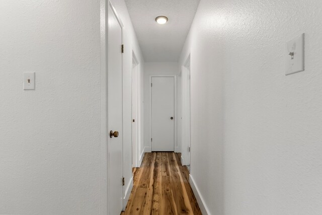 hall with hardwood / wood-style floors and a textured ceiling