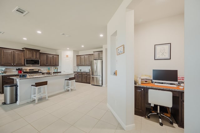 7521 Iron Mountain Rd, Odessa, TX 79765 - kitchen featuring stainless steel appliances, a kitchen breakfast bar, a desk, dark brown cabinetry, and recessed lighting