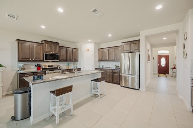 7521 Iron Mountain Rd, Odessa, TX 79765 - kitchen with stainless steel appliances, backsplash, a kitchen breakfast bar, light stone countertops, and a center island with sink