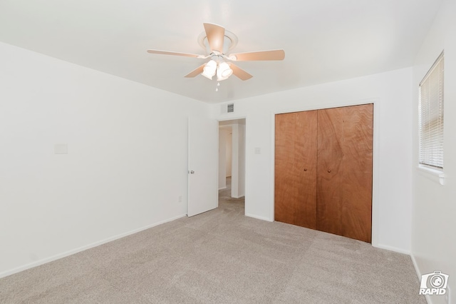 unfurnished bedroom featuring light carpet, a closet, baseboards, and a ceiling fan