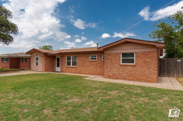 back of house with brick siding, a yard, and fence