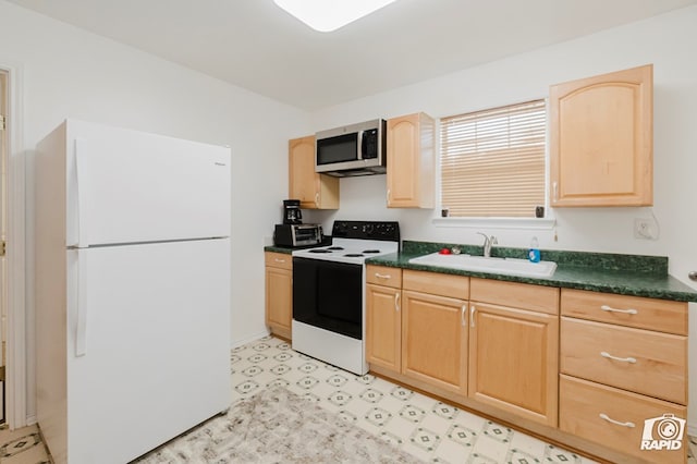 kitchen with light brown cabinetry, freestanding refrigerator, a sink, stainless steel microwave, and range with electric stovetop