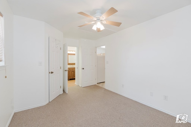 unfurnished room with light colored carpet, attic access, baseboards, and a ceiling fan