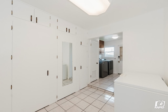 hall with washing machine and dryer and light tile patterned floors