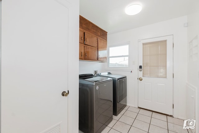 clothes washing area with light tile patterned floors, washing machine and dryer, and cabinet space