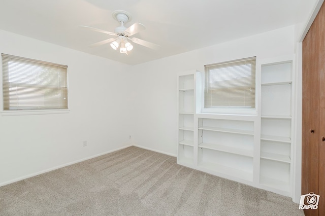 unfurnished room with a ceiling fan, baseboards, and light colored carpet