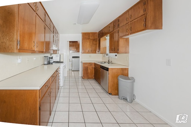 kitchen featuring light tile patterned floors, stainless steel dishwasher, brown cabinets, and a sink