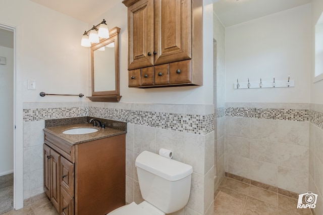 bathroom featuring tile patterned floors, tile walls, toilet, and wainscoting