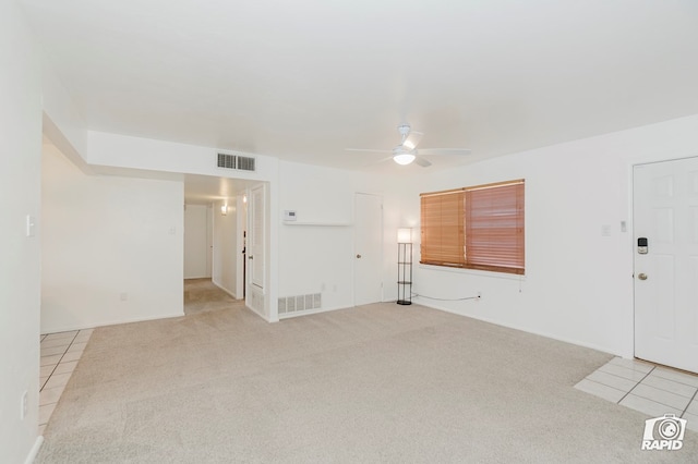 empty room featuring light colored carpet, visible vents, and a ceiling fan