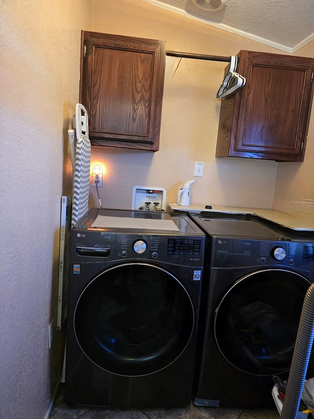 laundry room featuring cabinet space, washer and dryer, and a textured ceiling