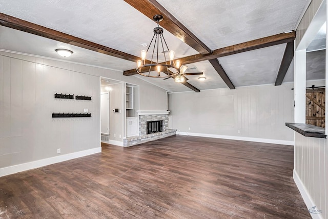 14038 W County Rd 123, Odessa, TX 79765 - unfurnished living room featuring dark wood-type flooring, beamed ceiling, a chandelier, a fireplace, and a barn door